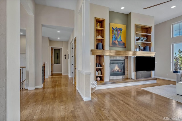 unfurnished living room featuring built in shelves and light hardwood / wood-style flooring