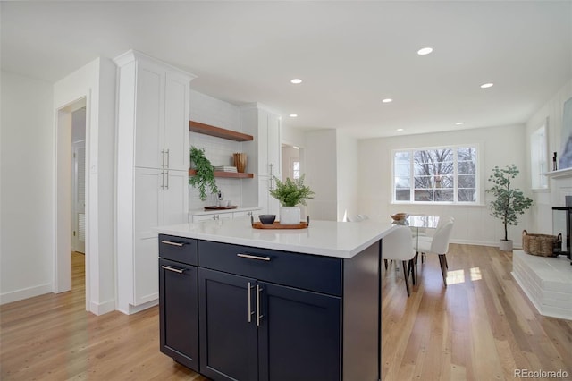 kitchen with light countertops, light wood-type flooring, open shelves, and white cabinets