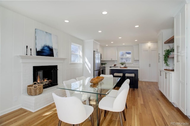 dining room featuring recessed lighting, a fireplace, and light wood finished floors