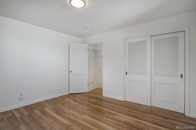 unfurnished bedroom with light wood-type flooring, baseboards, and a closet