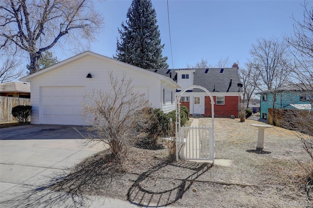 view of front of property with an attached garage, brick siding, fence, driveway, and a chimney