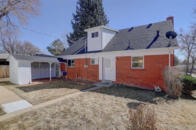 rear view of house with a shingled roof, fence, a lawn, and brick siding