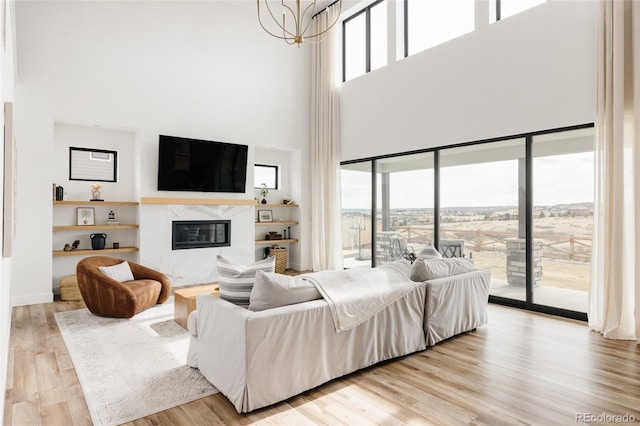 17252 Rose Mallow Ave, Parker, CO 80134 - living room featuring a healthy amount of sunlight, wood finished floors, a high end fireplace, and an inviting chandelier