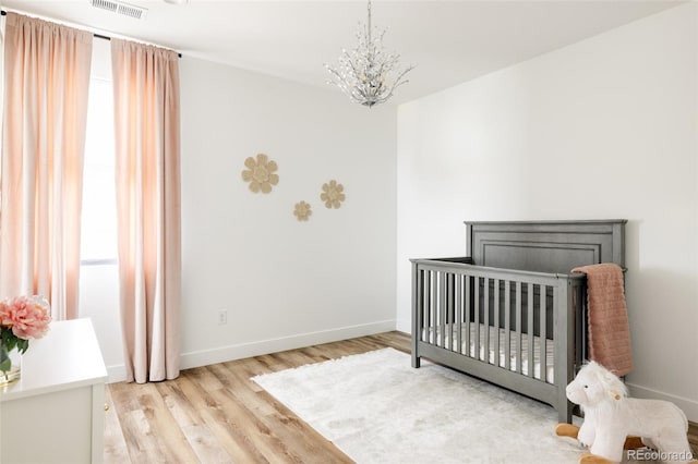 17252 Rose Mallow Ave, Parker, CO 80134 - bedroom featuring visible vents, baseboards, a crib, a chandelier, and light wood-style floors
