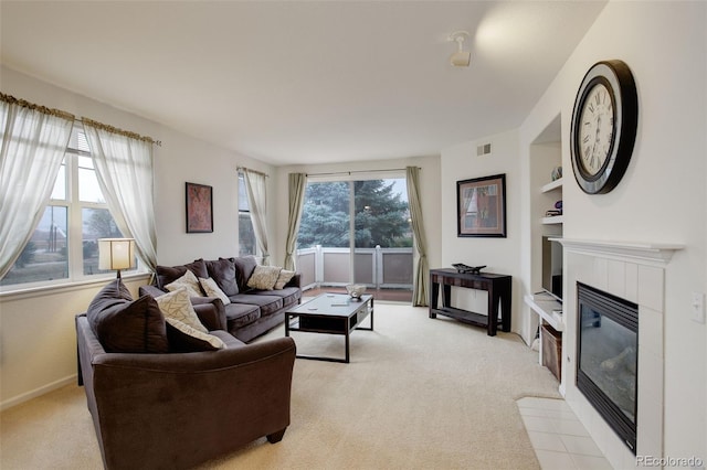 living room with light colored carpet, built in shelves, and a tile fireplace