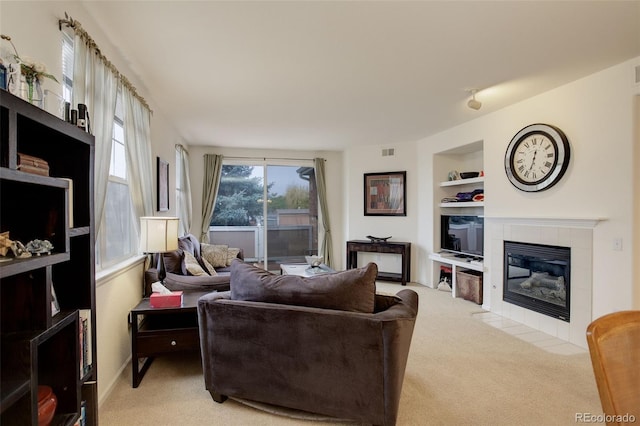 carpeted living room featuring built in shelves and a tiled fireplace