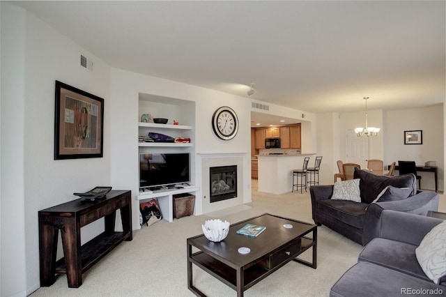 living room with light carpet, built in features, and an inviting chandelier