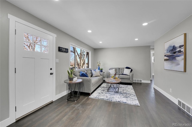 living area featuring visible vents, dark wood finished floors, and baseboards