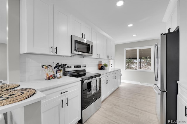 kitchen featuring white cabinetry, appliances with stainless steel finishes, decorative backsplash, and light wood-style flooring