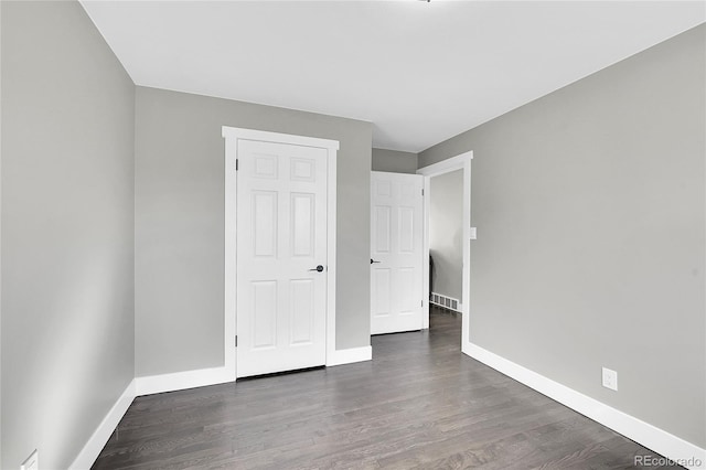 unfurnished bedroom featuring visible vents, baseboards, and wood finished floors