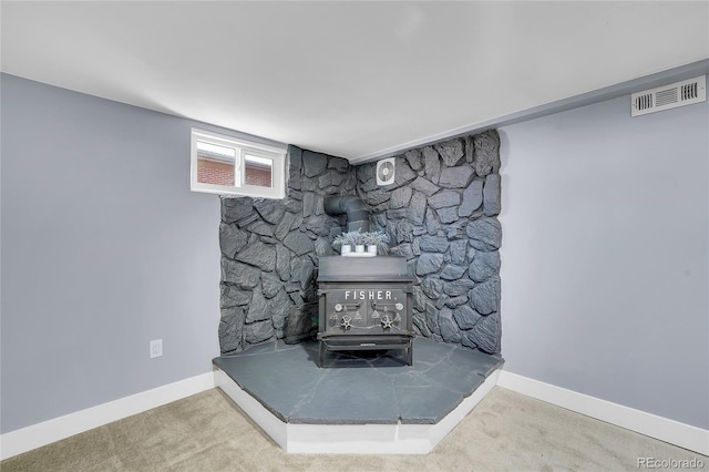 interior details with visible vents, carpet, a wood stove, and baseboards