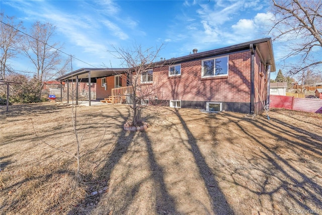 rear view of property with covered porch, fence, and brick siding