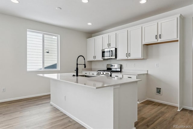 kitchen featuring a center island with sink, white cabinets, stainless steel appliances, and sink