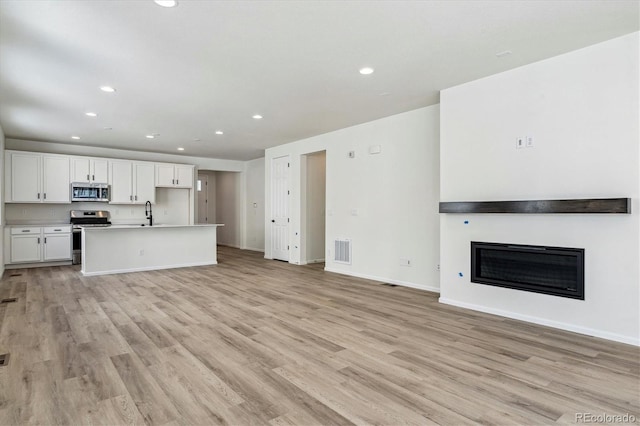 unfurnished living room featuring light wood-type flooring and sink