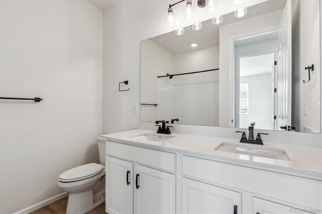 bathroom with a shower, hardwood / wood-style floors, vanity, and toilet