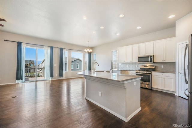 6093 Rowdy Dr, Colorado Springs, CO 80924 - kitchen with tasteful backsplash, white cabinets, stainless steel appliances, a center island with sink, and dark wood finished floors