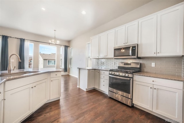 6093 Rowdy Dr, Colorado Springs, CO 80924 - kitchen featuring a sink, tasteful backsplash, dark wood-style flooring, a chandelier, and appliances with stainless steel finishes