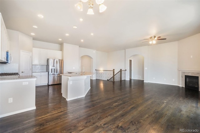 6093 Rowdy Dr, Colorado Springs, CO 80924 - kitchen featuring arched walkways, dark wood finished floors, open floor plan, ceiling fan with notable chandelier, and appliances with stainless steel finishes