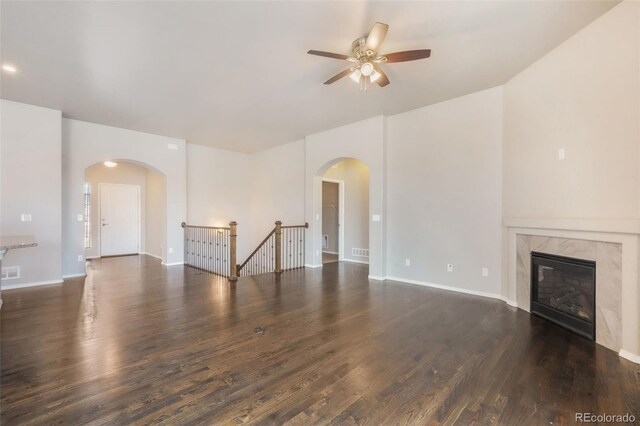 6093 Rowdy Dr, Colorado Springs, CO 80924 - unfurnished living room featuring arched walkways, a high end fireplace, wood finished floors, and a ceiling fan