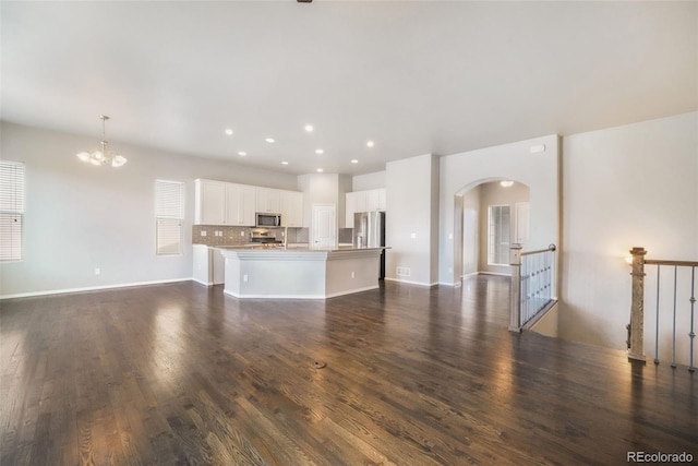 6093 Rowdy Dr, Colorado Springs, CO 80924 - unfurnished living room with recessed lighting, dark wood finished floors, an inviting chandelier, arched walkways, and baseboards