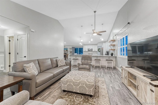 living room featuring light hardwood / wood-style flooring, vaulted ceiling, and ceiling fan