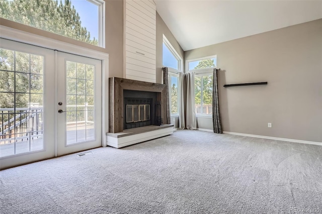 9385 Pepperwood Ln, Highlands Ranch, CO 80126 - unfurnished living room featuring carpet flooring, high vaulted ceiling, a glass covered fireplace, and french doors