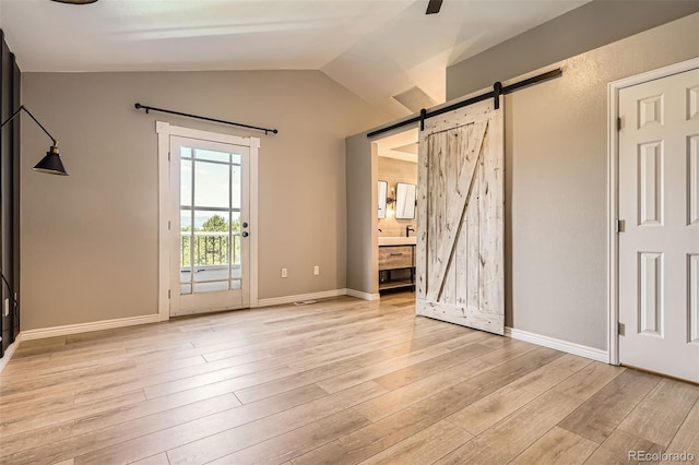 9385 Pepperwood Ln, Highlands Ranch, CO 80126 - unfurnished bedroom featuring a barn door, access to outside, light wood finished floors, vaulted ceiling, and ensuite bath