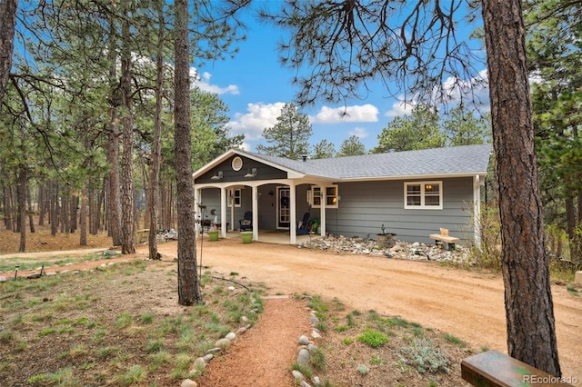 single story home featuring a porch, driveway, and roof with shingles