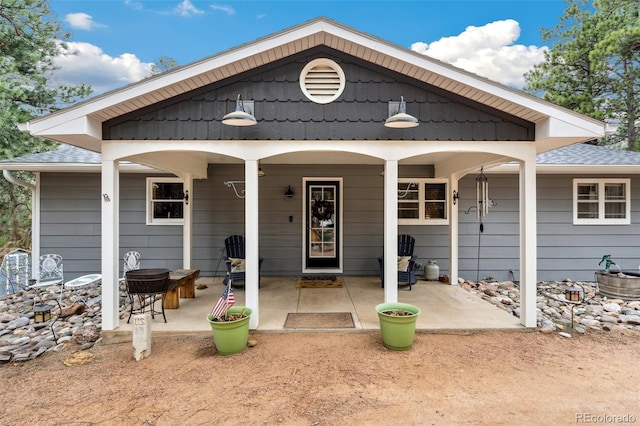 back of property featuring a patio area and a shingled roof