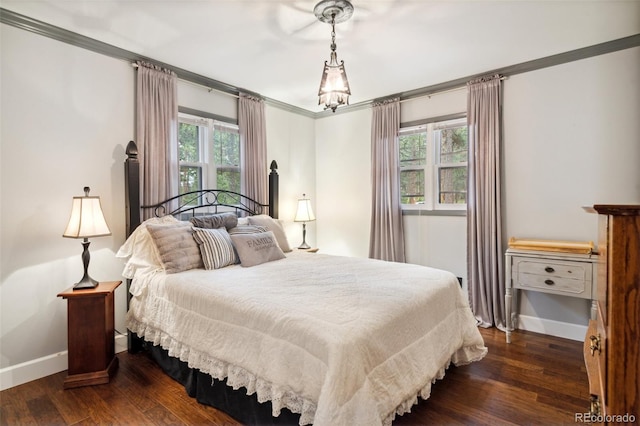 bedroom with dark wood-style flooring, ornamental molding, and baseboards