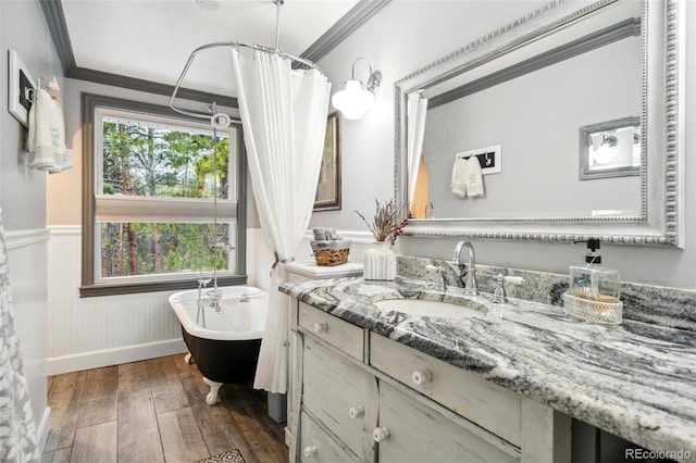bathroom with a wainscoted wall, vanity, crown molding, wood-type flooring, and a freestanding bath