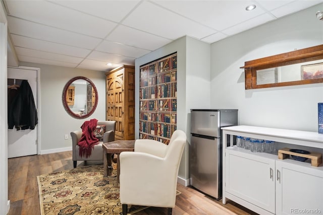 living area featuring a paneled ceiling, baseboards, light wood-type flooring, and recessed lighting