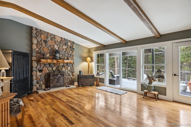 living area with lofted ceiling with beams, a fireplace, and wood finished floors