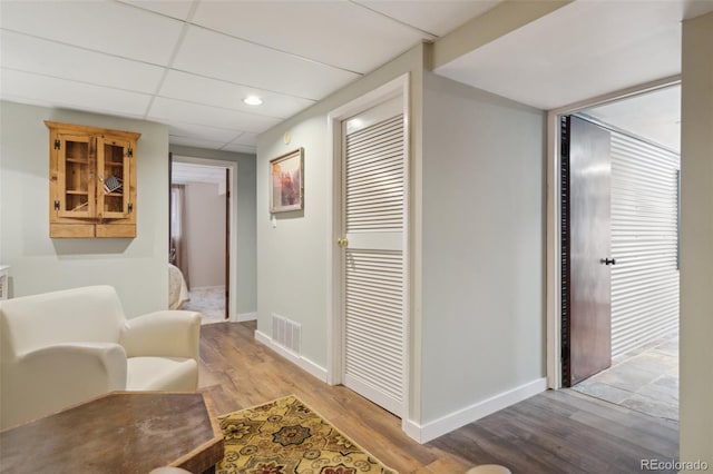 hallway with light wood-style flooring, recessed lighting, baseboards, visible vents, and a paneled ceiling
