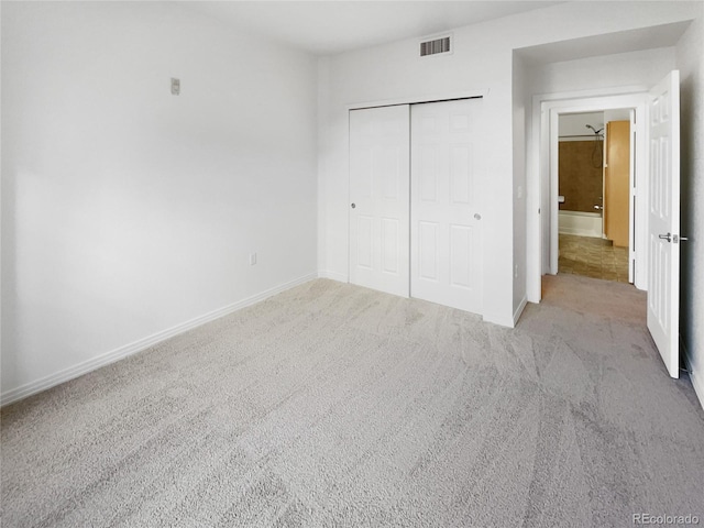 unfurnished bedroom featuring light colored carpet and a closet