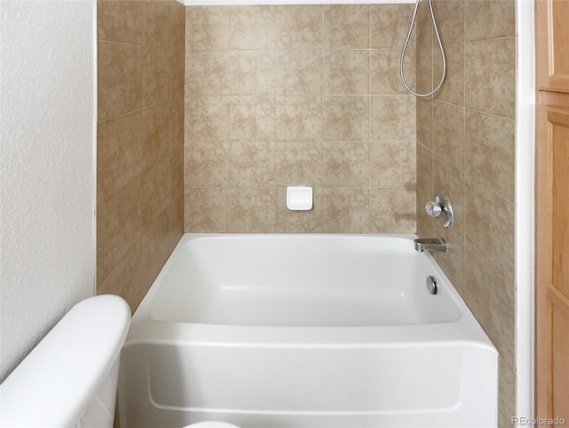 bathroom featuring tiled shower / bath combo and toilet