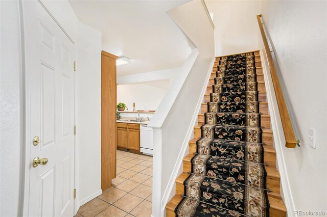 stairway featuring tile patterned flooring and sink