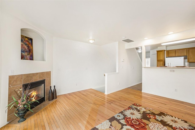 unfurnished living room with a tile fireplace and light wood-type flooring