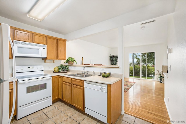 kitchen featuring kitchen peninsula, white appliances, sink, and light tile patterned floors