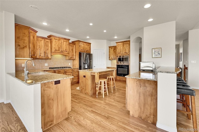 19045 Shiloh Ranch Dr, Colorado Springs, CO 80908 - kitchen featuring stainless steel appliances, a sink, a breakfast bar, light wood finished floors, and a peninsula