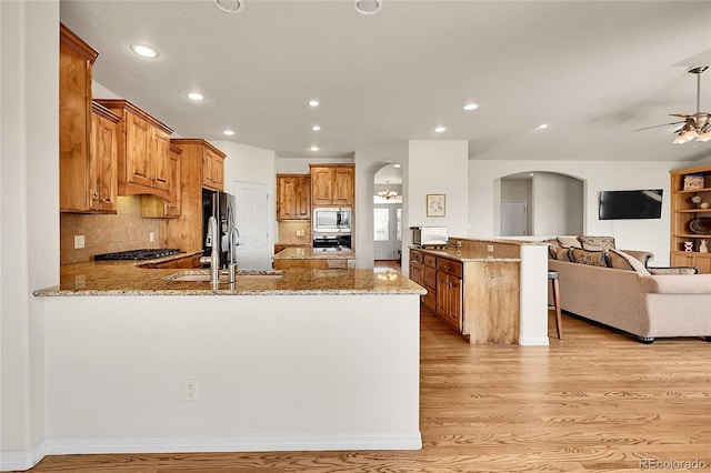19045 Shiloh Ranch Dr, Colorado Springs, CO 80908 - kitchen featuring a peninsula, arched walkways, stainless steel microwave, ceiling fan, and open floor plan