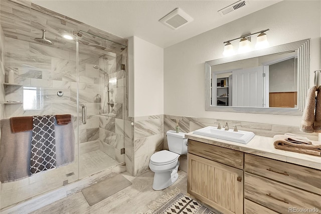 19045 Shiloh Ranch Dr, Colorado Springs, CO 80908 - full bathroom featuring toilet, vanity, a shower stall, tile walls, and wainscoting