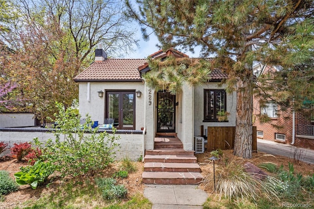 mediterranean / spanish home featuring a chimney, a tiled roof, french doors, and stucco siding