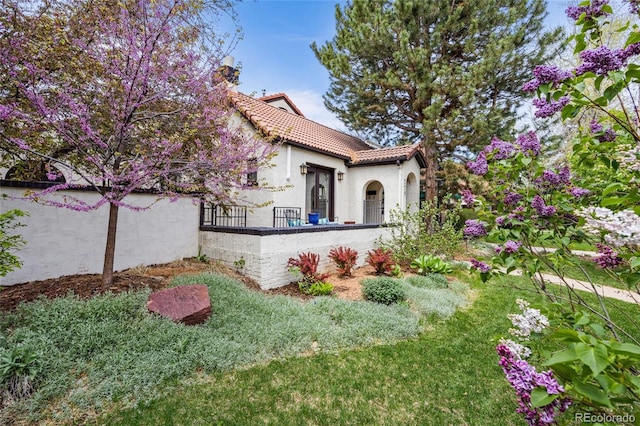 view of side of home featuring a tile roof, a chimney, and stucco siding