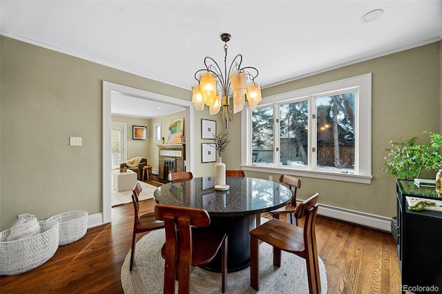 dining room featuring a baseboard radiator, a fireplace, a chandelier, and dark wood finished floors