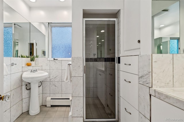 full bath featuring tile patterned floors, baseboard heating, a healthy amount of sunlight, a shower stall, and tile walls