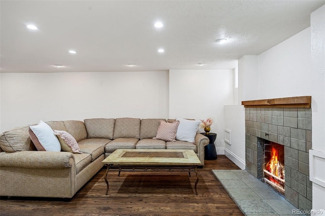 living room featuring baseboards, a fireplace, dark wood finished floors, and recessed lighting