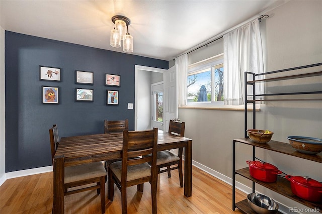 dining space with baseboards and light wood-style flooring