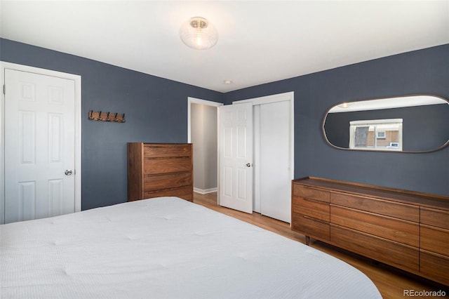 bedroom with baseboards, a closet, and wood finished floors
