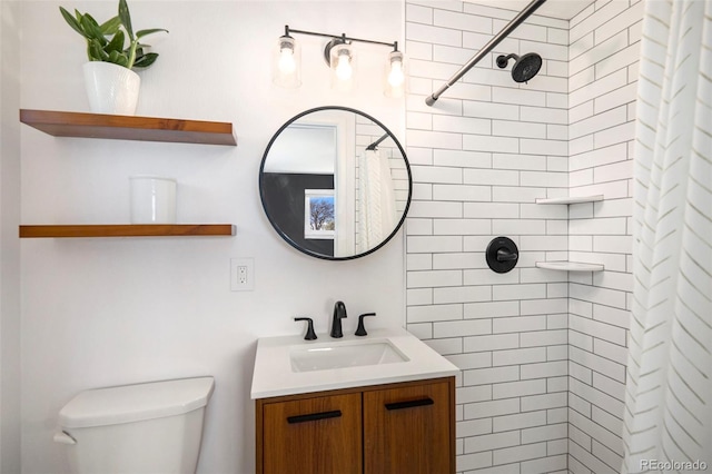 bathroom with toilet, a tile shower, and vanity